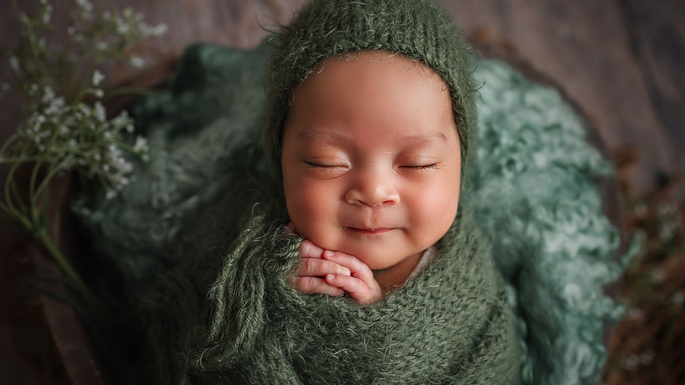 Baby sleeping calmly in a green blanket without any symptoms of Infant Shudder Syndrome 