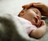 Mom caressing baby's head to calm Infant Shudder Syndrome